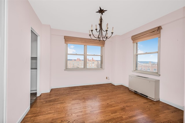 unfurnished dining area featuring hardwood / wood-style flooring, radiator, and a healthy amount of sunlight