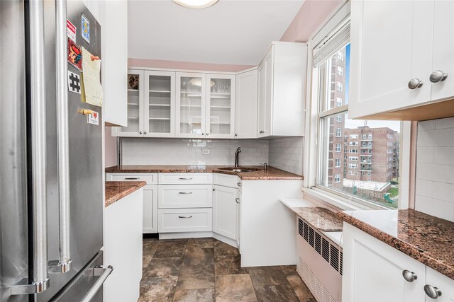 kitchen with stainless steel fridge, white cabinetry, and dark stone countertops