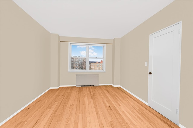 spare room featuring radiator and light hardwood / wood-style floors