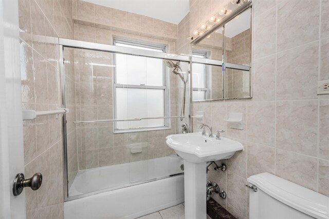 bathroom with tile patterned floors, toilet, enclosed tub / shower combo, and tile walls