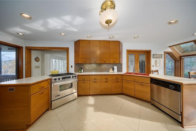 kitchen featuring a wealth of natural light, kitchen peninsula, backsplash, and appliances with stainless steel finishes