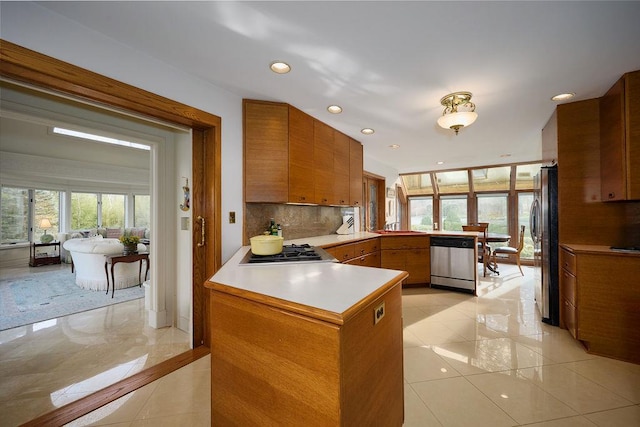 kitchen featuring kitchen peninsula, appliances with stainless steel finishes, decorative backsplash, sink, and light tile patterned floors