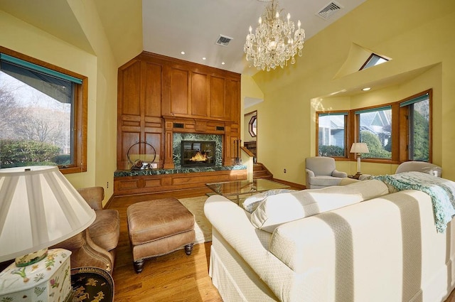 living room with a fireplace, vaulted ceiling, light hardwood / wood-style flooring, and a notable chandelier