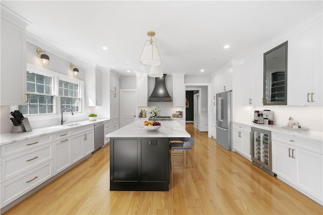 kitchen with beverage cooler, stainless steel appliances, a kitchen island, wall chimney exhaust hood, and pendant lighting