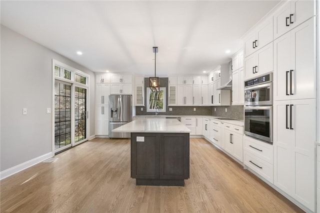 kitchen with decorative light fixtures, light countertops, appliances with stainless steel finishes, white cabinets, and a kitchen island