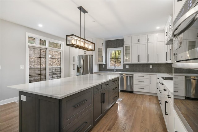 kitchen featuring decorative light fixtures, appliances with stainless steel finishes, glass insert cabinets, white cabinets, and a kitchen island