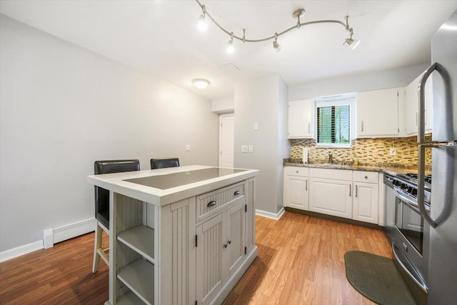 kitchen with white cabinets, a center island, light hardwood / wood-style flooring, and a baseboard heating unit