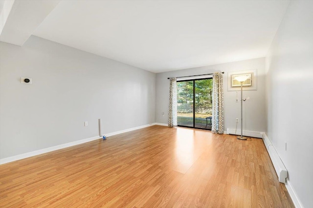 spare room with baseboard heating and light hardwood / wood-style flooring