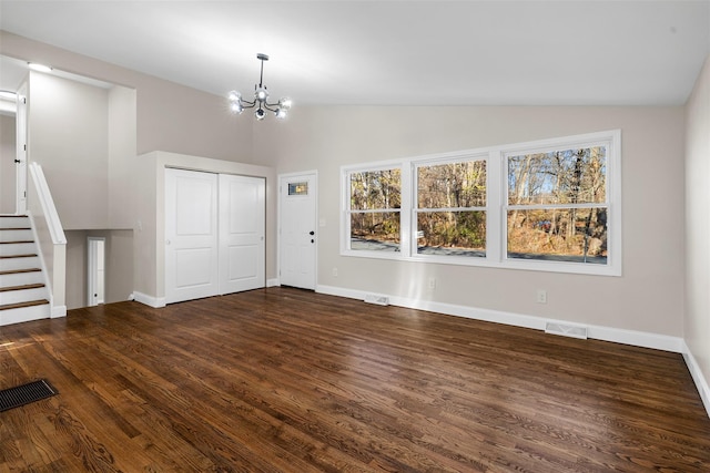 unfurnished living room featuring vaulted ceiling, dark hardwood / wood-style floors, and a notable chandelier