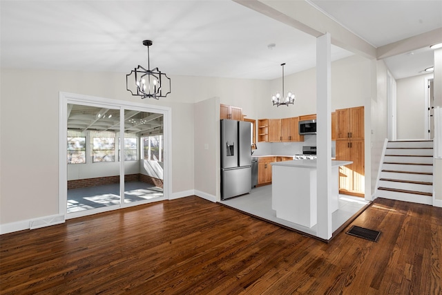 kitchen featuring lofted ceiling, hanging light fixtures, appliances with stainless steel finishes, wood-type flooring, and a chandelier