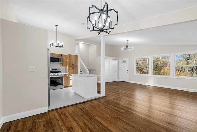 kitchen with hanging light fixtures, stainless steel appliances, vaulted ceiling, and hardwood / wood-style flooring