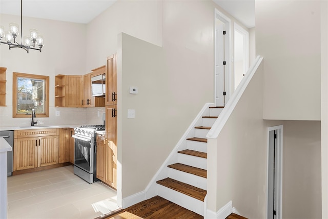 kitchen with appliances with stainless steel finishes, backsplash, sink, decorative light fixtures, and a chandelier