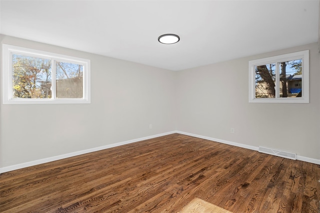 spare room with dark hardwood / wood-style floors and a healthy amount of sunlight