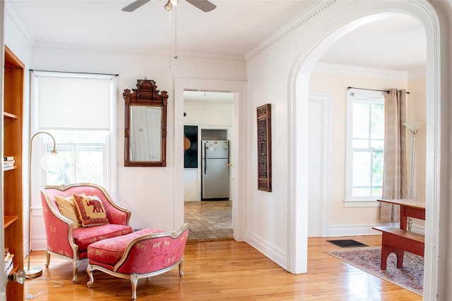 sitting room with ceiling fan, light wood-type flooring, and ornamental molding