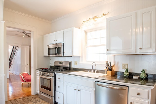 kitchen with white cabinets, sink, ornamental molding, and stainless steel appliances