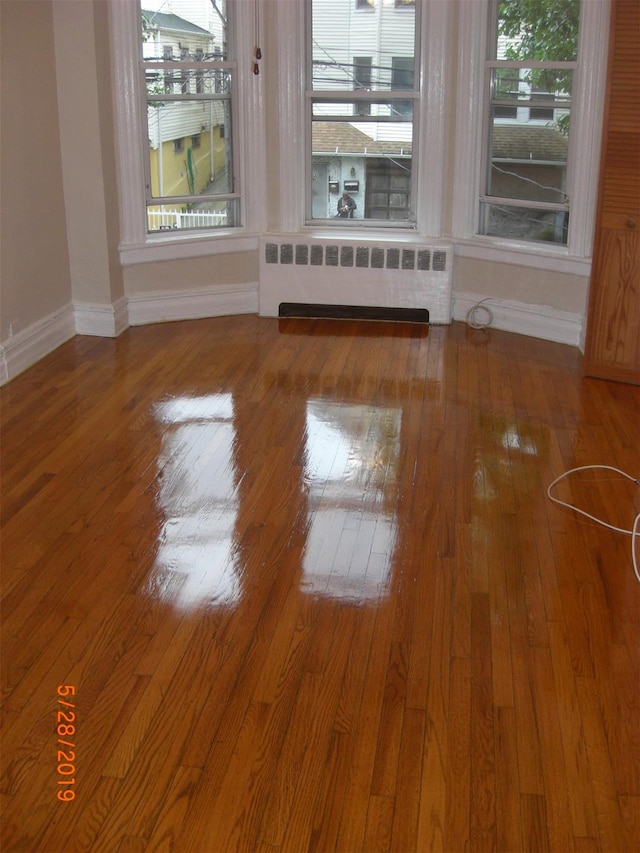 spare room with a wealth of natural light, radiator heating unit, and hardwood / wood-style flooring