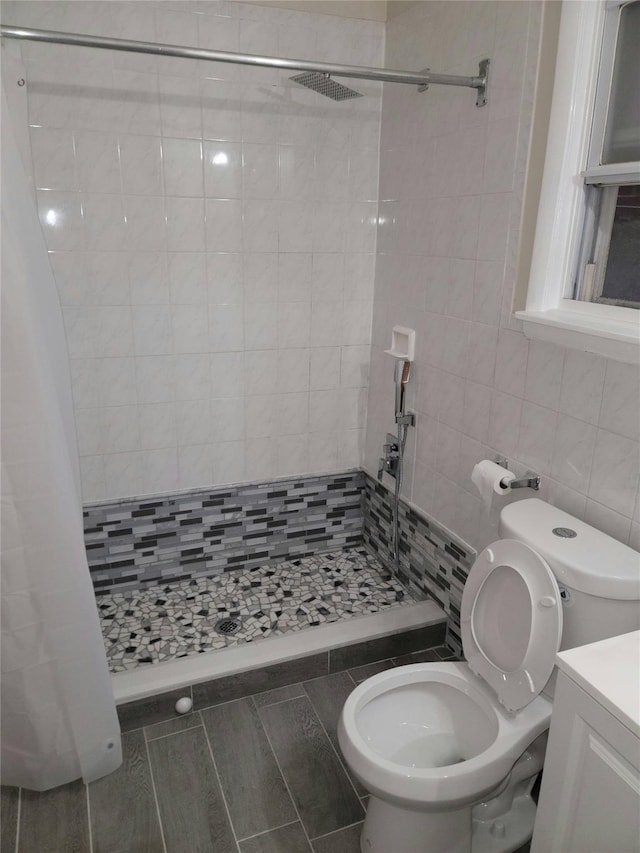 bathroom featuring vanity, toilet, tile walls, and walk in shower