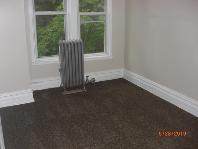 unfurnished room featuring carpet and radiator