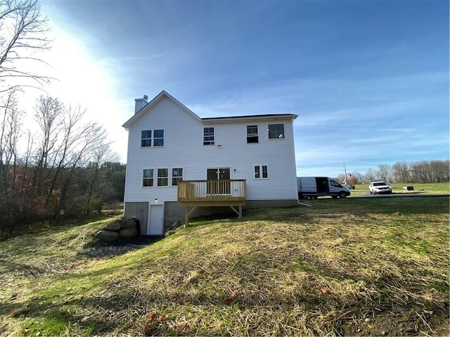 back of property with a yard, a chimney, and a wooden deck