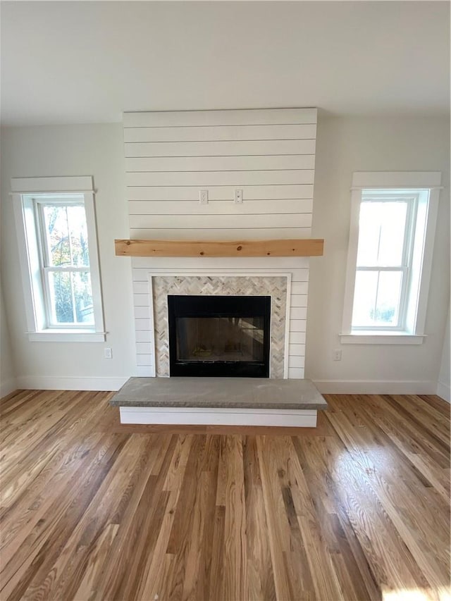 room details with baseboards, wood finished floors, and a glass covered fireplace