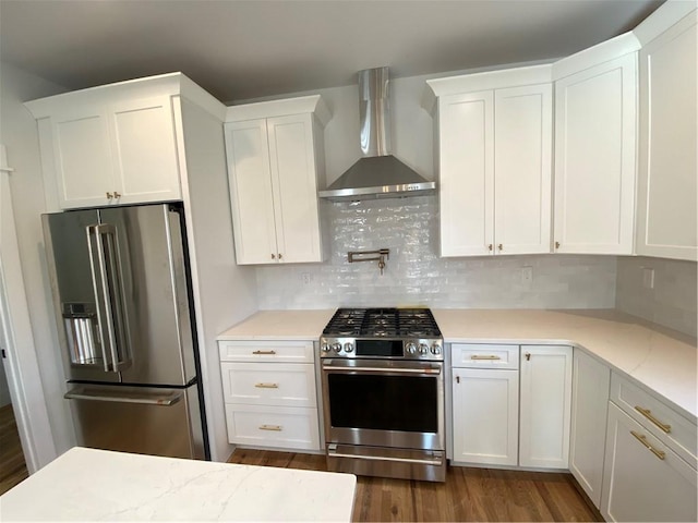 kitchen with white cabinets, wall chimney exhaust hood, dark hardwood / wood-style flooring, and stainless steel appliances