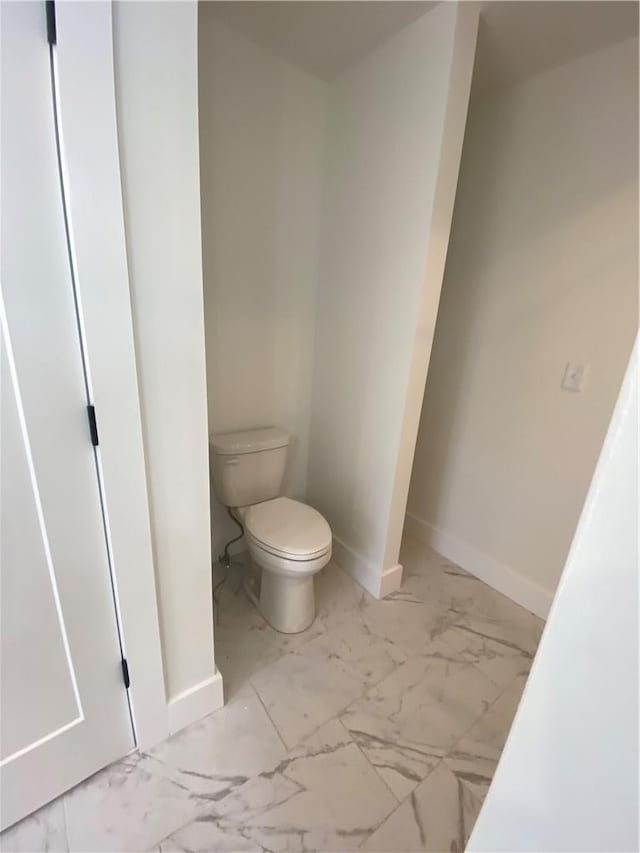 bathroom featuring marble finish floor, toilet, and baseboards