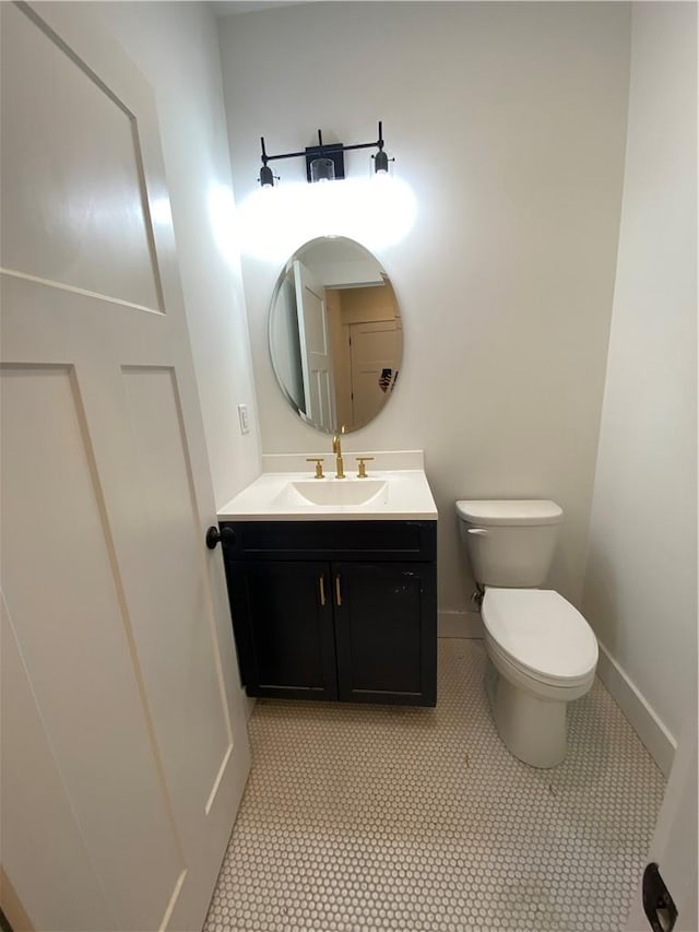 bathroom with toilet, baseboards, and vanity