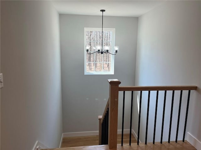 staircase with hardwood / wood-style floors and a notable chandelier