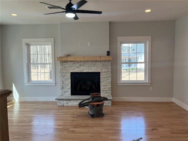 living room with a fireplace, light hardwood / wood-style flooring, and ceiling fan