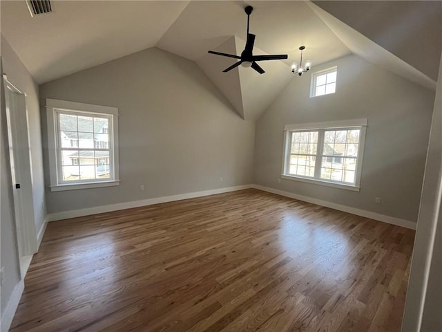 unfurnished living room featuring ceiling fan with notable chandelier, dark hardwood / wood-style flooring, and vaulted ceiling