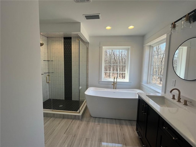 bathroom featuring hardwood / wood-style floors, vanity, and shower with separate bathtub