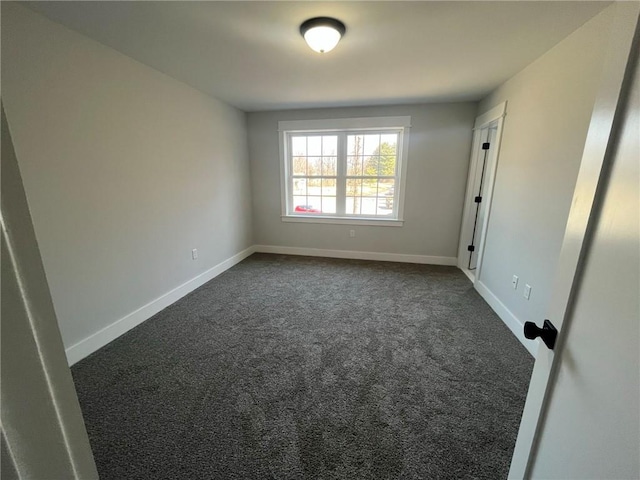 unfurnished room featuring dark colored carpet