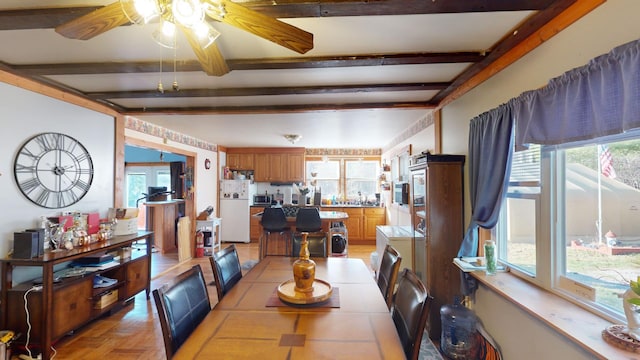 dining space with beam ceiling, light parquet flooring, and plenty of natural light