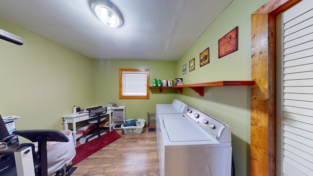 clothes washing area with light hardwood / wood-style flooring, washer and dryer, and a textured ceiling