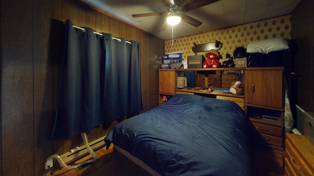 bedroom with ceiling fan, wooden walls, and a baseboard heating unit