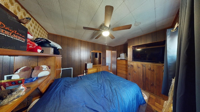 bedroom with ceiling fan and wood walls