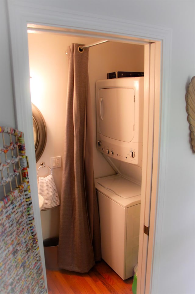 clothes washing area featuring light hardwood / wood-style floors and stacked washer / drying machine