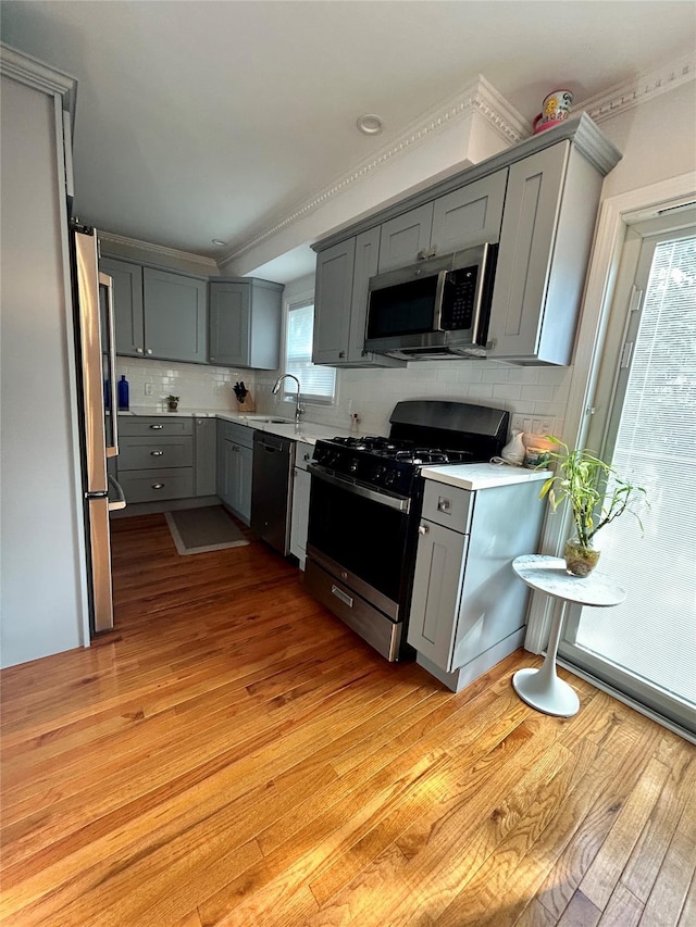 kitchen featuring appliances with stainless steel finishes, light hardwood / wood-style flooring, gray cabinetry, and sink