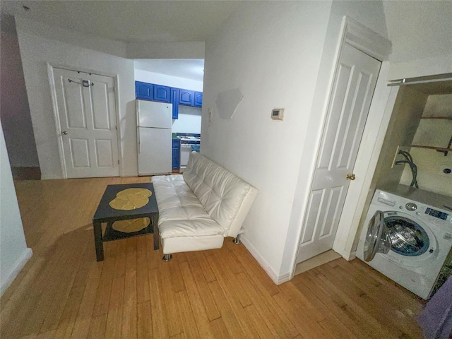 sitting room featuring washer / dryer, light wood-type flooring, and baseboards