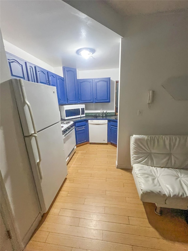 kitchen featuring blue cabinetry, light wood-style floors, white appliances, and dark countertops