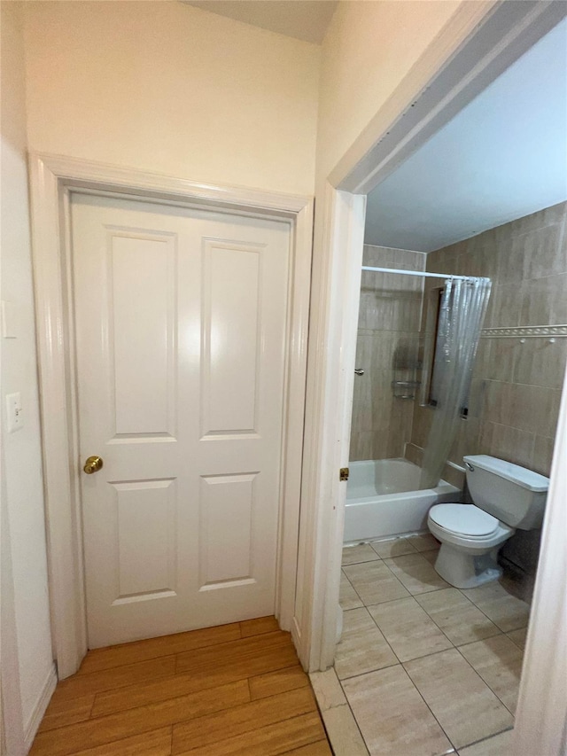 full bath with toilet, wood finished floors, and shower / bath combination with curtain