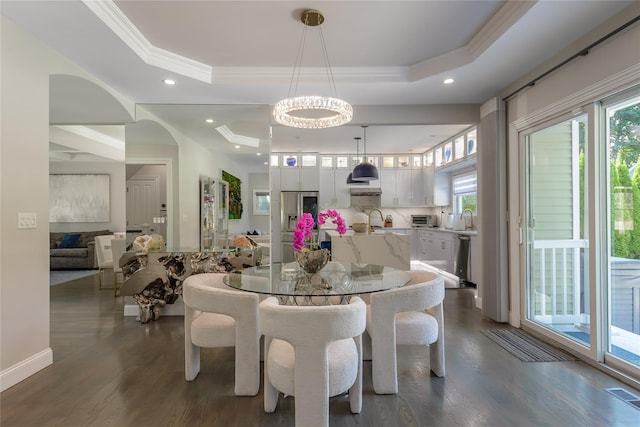 dining space with a notable chandelier, plenty of natural light, dark hardwood / wood-style floors, and a raised ceiling