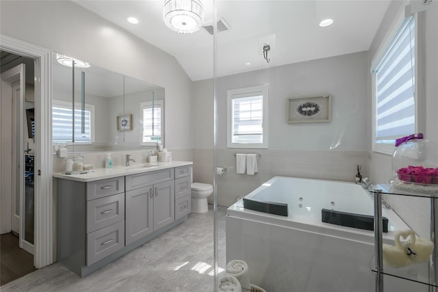 bathroom featuring a tub to relax in, vanity, vaulted ceiling, tile walls, and toilet