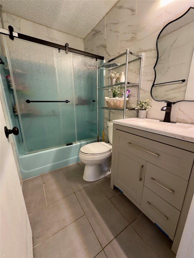 full bathroom with combined bath / shower with glass door, tile patterned floors, a textured ceiling, toilet, and vanity