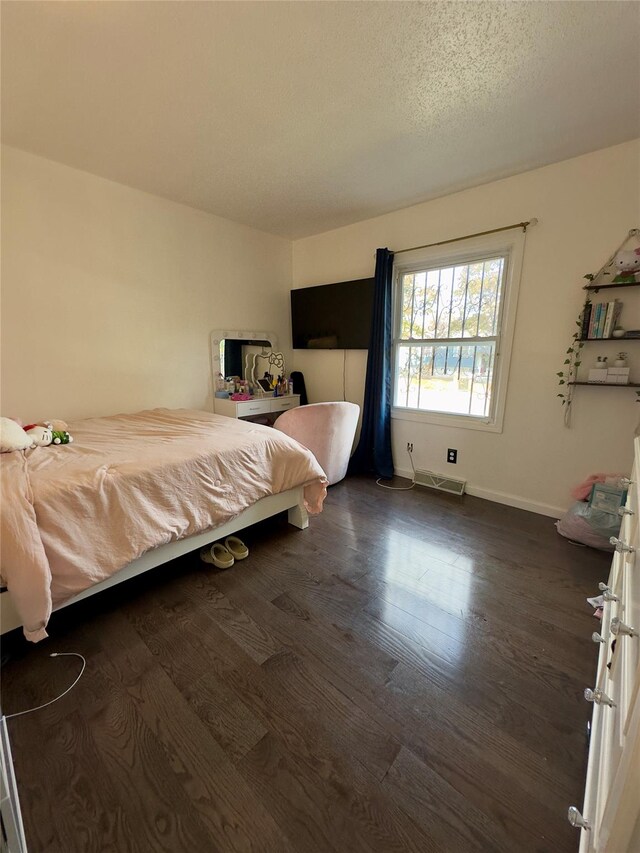 bedroom with dark hardwood / wood-style flooring and a textured ceiling