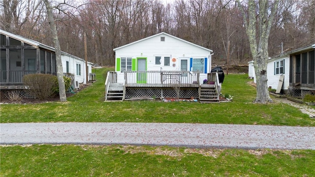 view of front facade with a sunroom, a deck, and a front yard