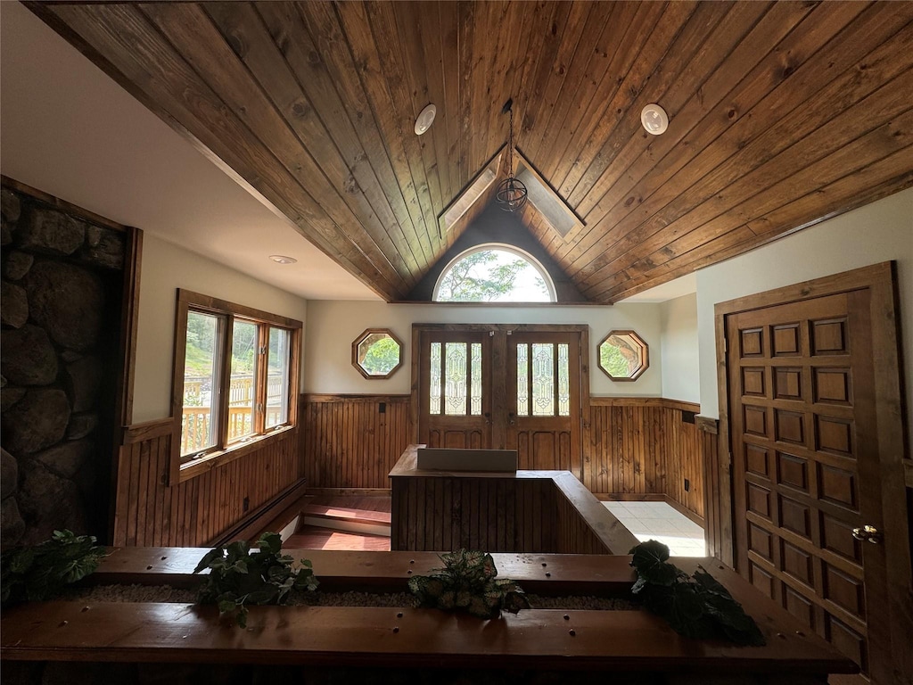 foyer entrance with wooden walls, french doors, wood ceiling, and lofted ceiling