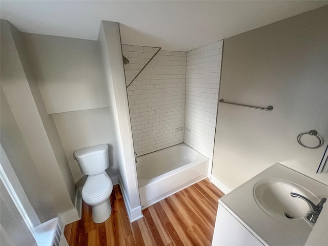 full bathroom with vanity, hardwood / wood-style floors, tiled shower / bath, and toilet