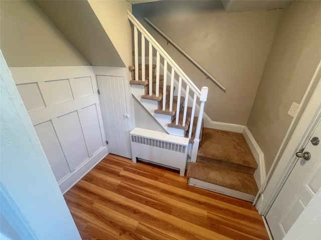 staircase featuring radiator heating unit and hardwood / wood-style floors