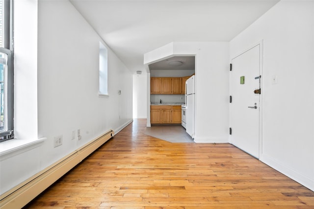 interior space featuring light wood-type flooring, baseboard heating, and sink